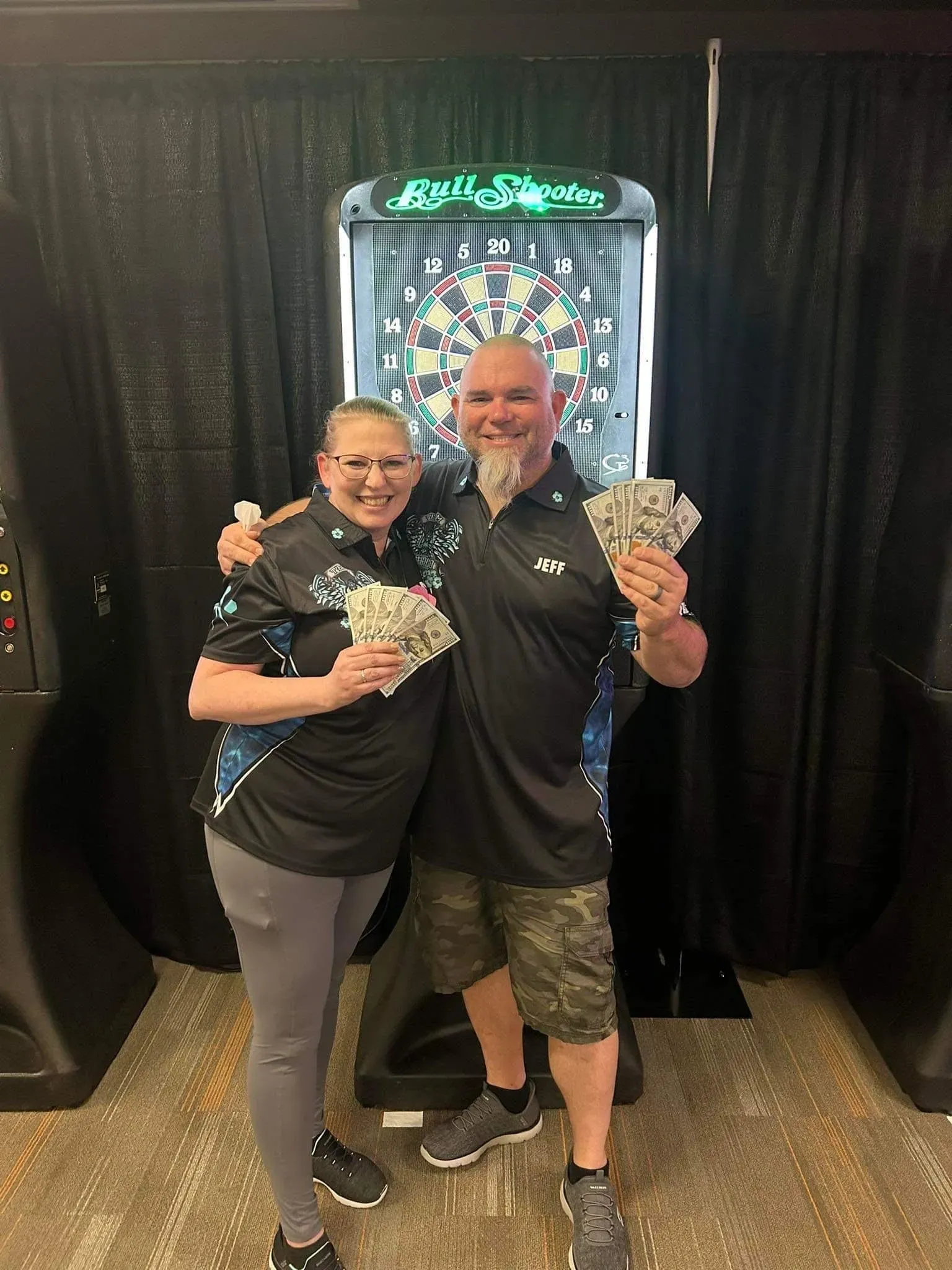 Winners posing with money and dartboard