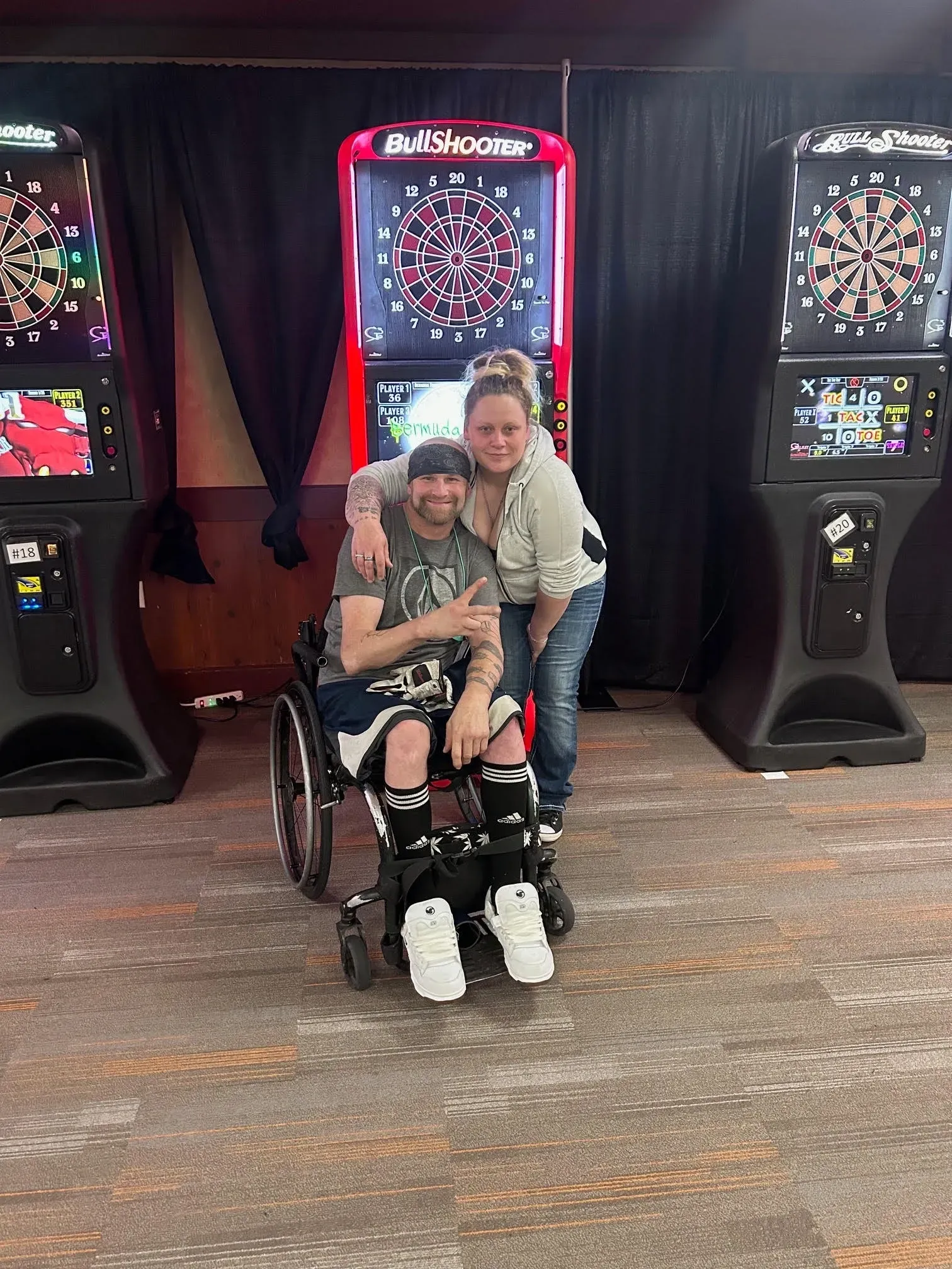 Smiling pair in front of dart machines