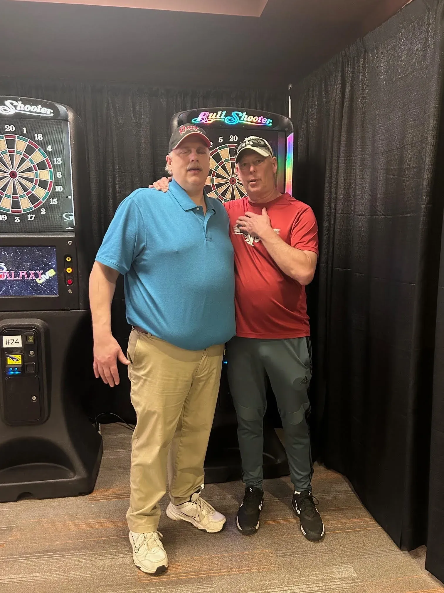 Friends standing by electronic dartboards