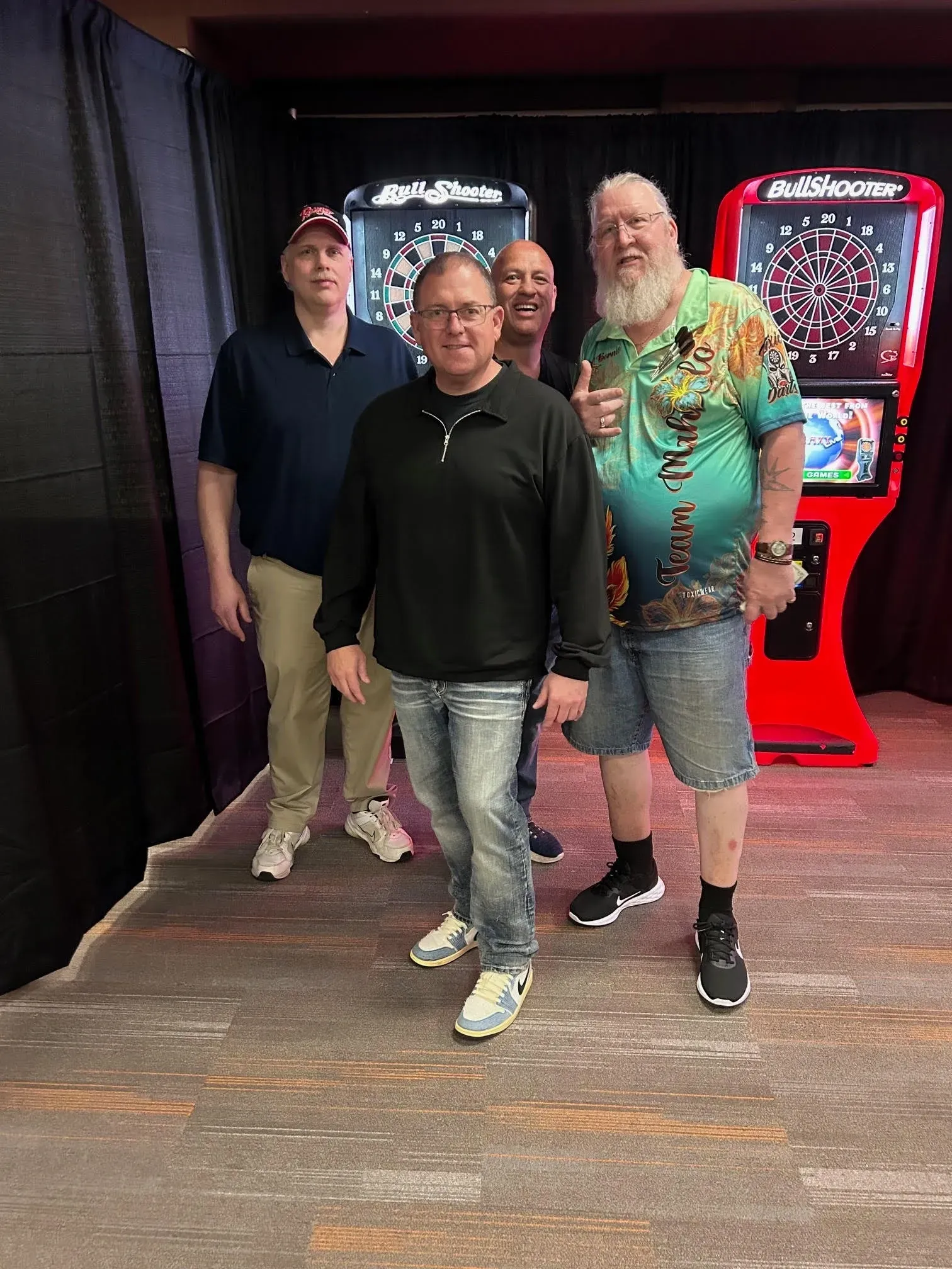 Group posing by dartboard machines