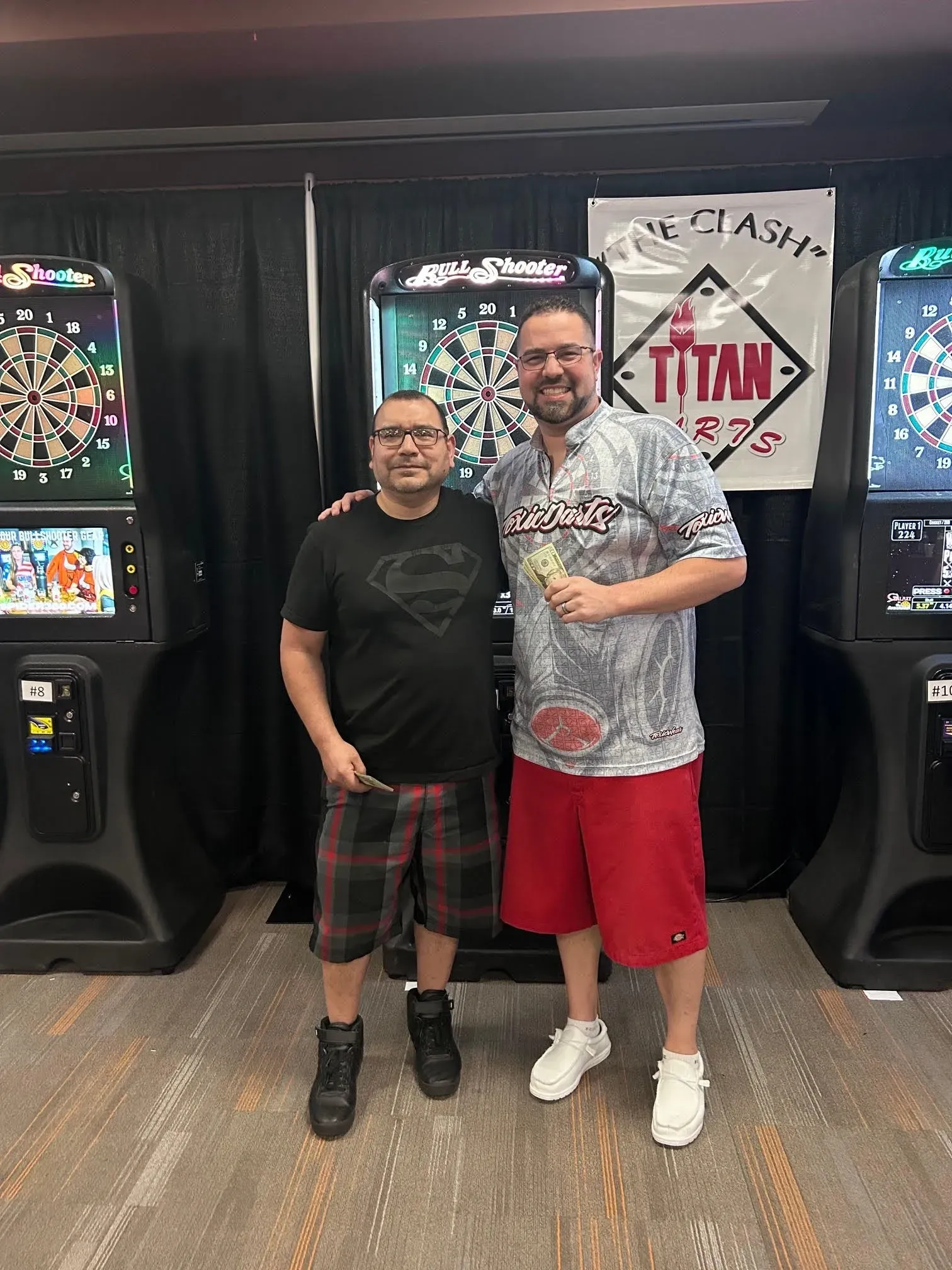 Two men standing by dart machines
