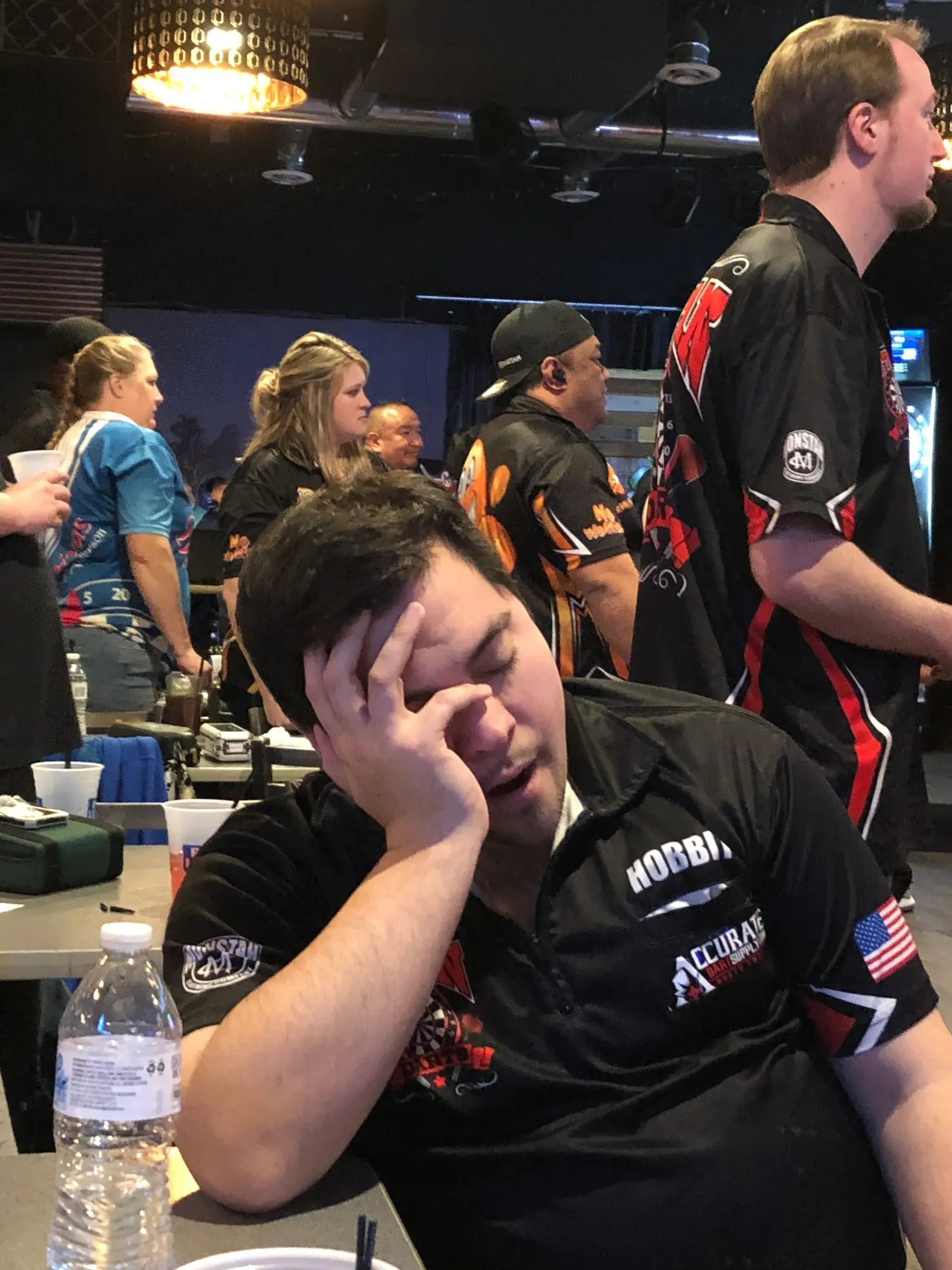 Man resting head in busy gaming venue