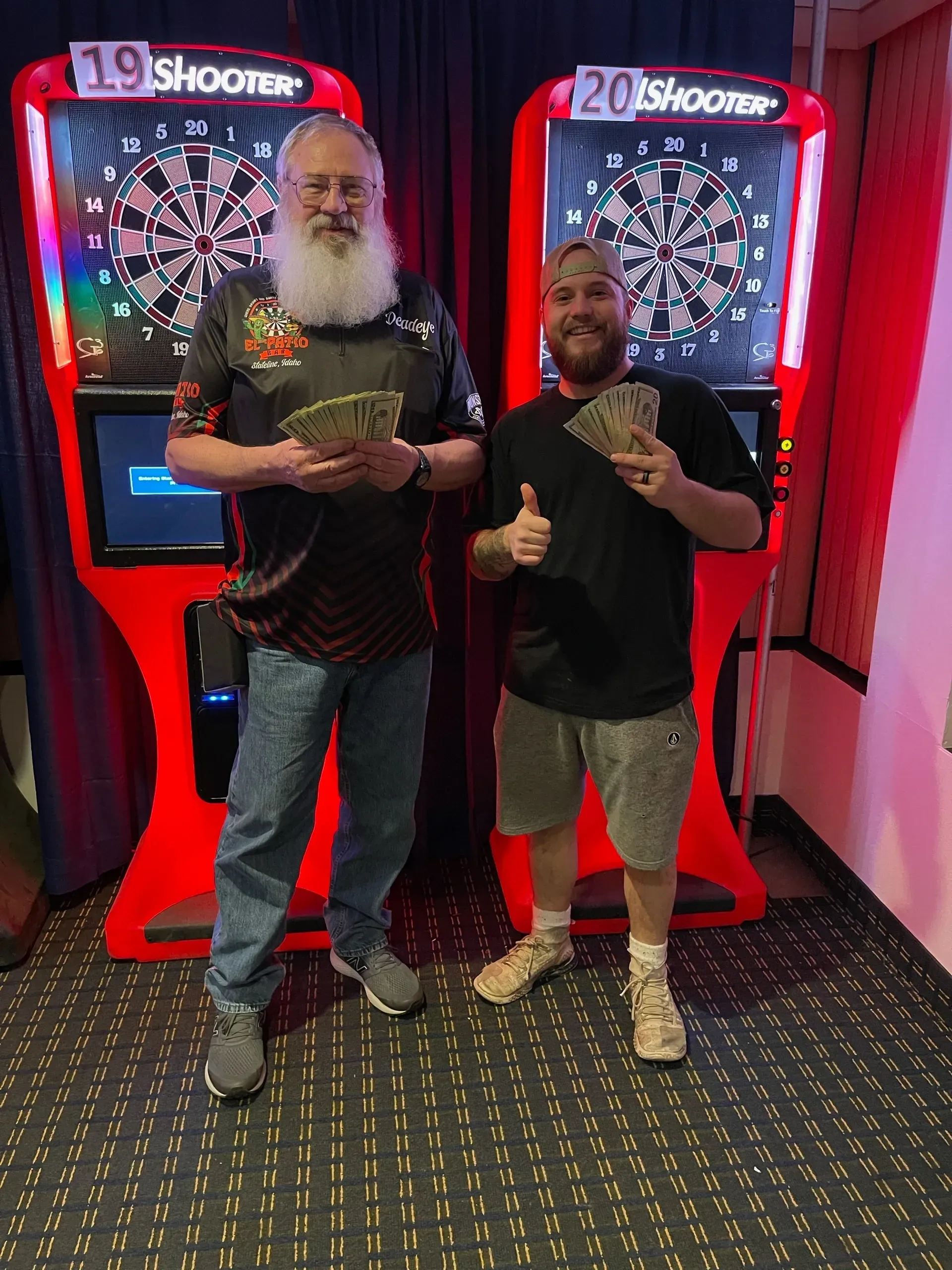 Smiling duo with cash at arcade.