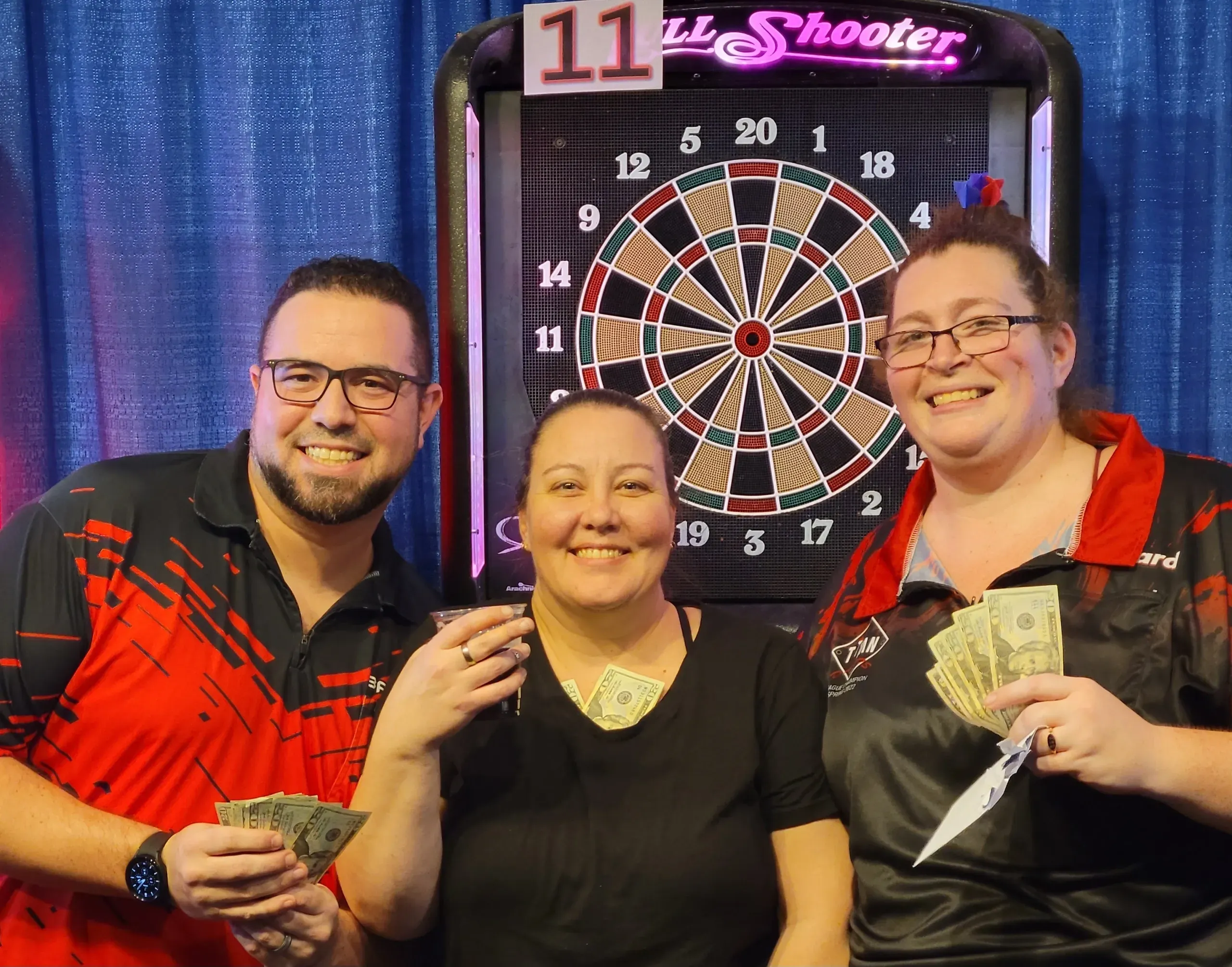 People smiling with dartboard and cash