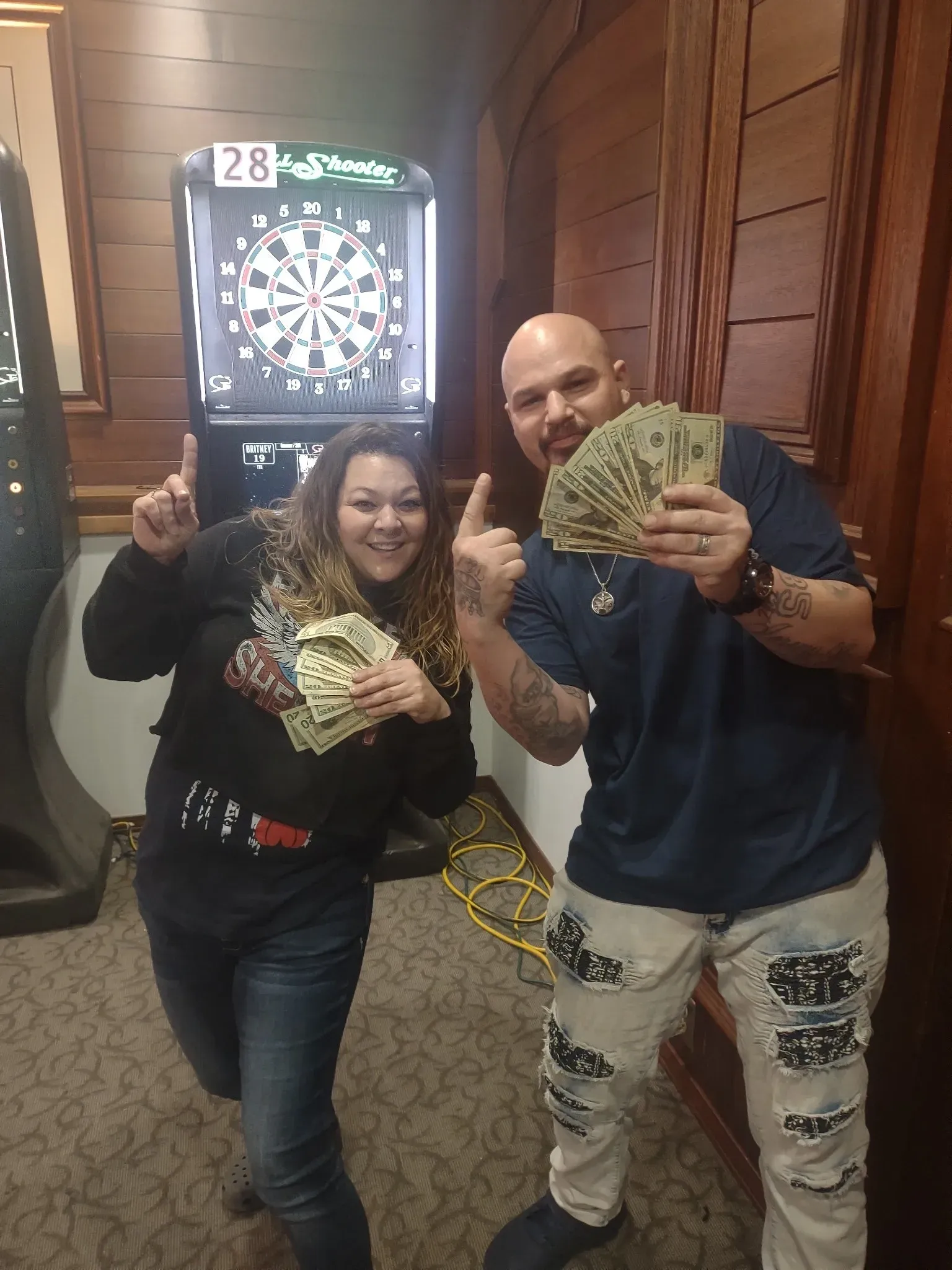 Happy pair celebrating with cash and darts