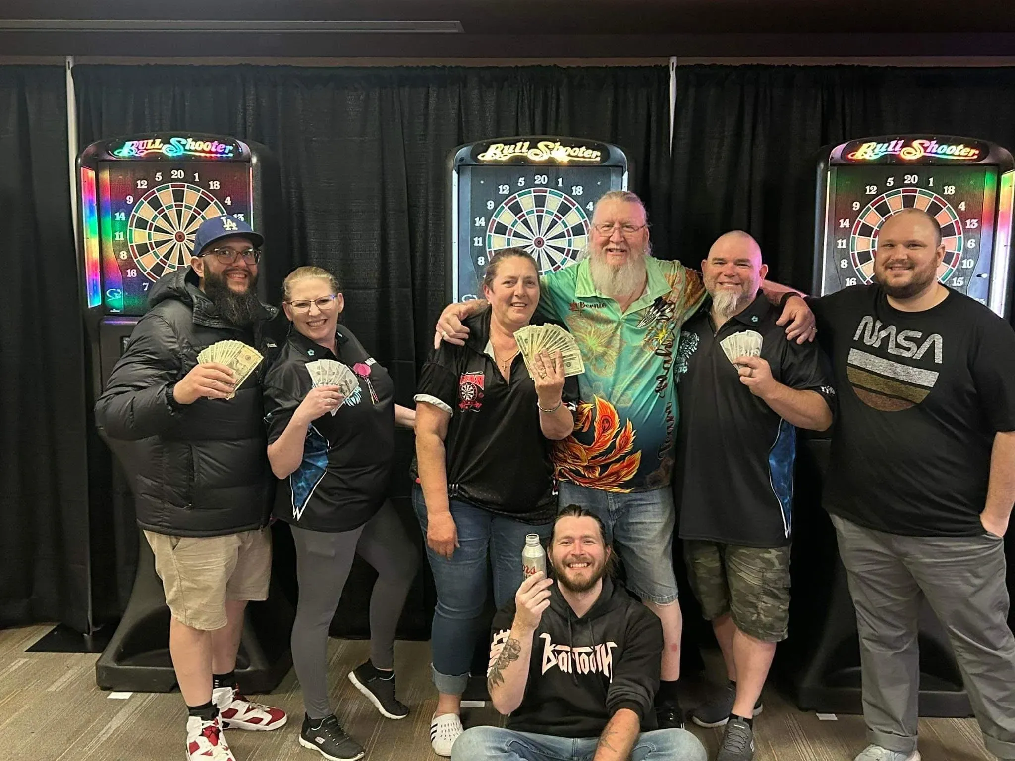 Group celebrating with money by dartboards